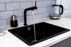 A kitchen sink with a black faucet and a coffee maker on the counter.