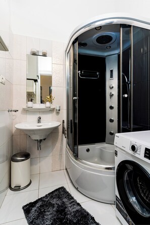 Une salle de bain moderne équipée d’une douche intégrée, d’un lavabo et d’un lave-linge.