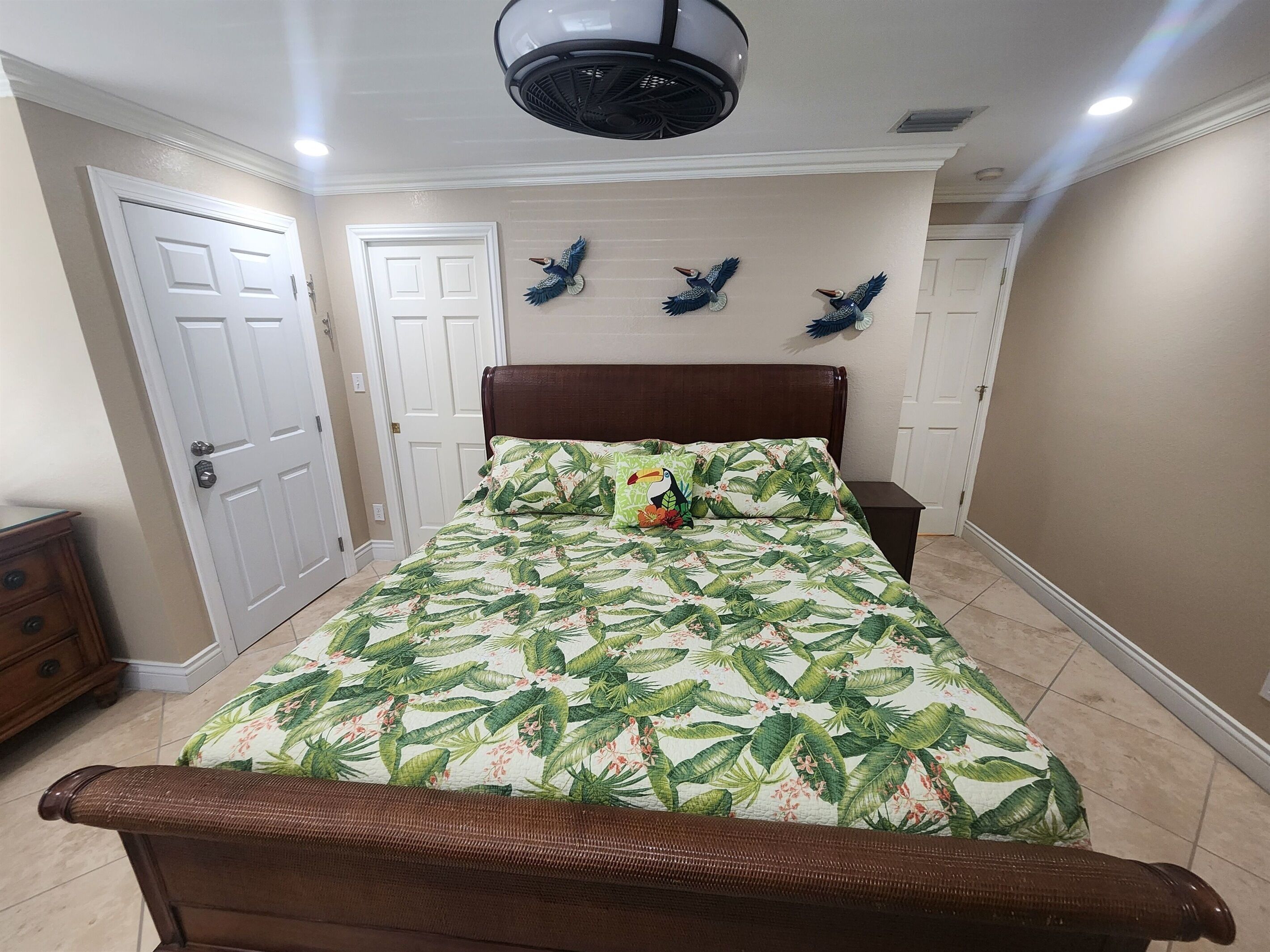 A bedroom with a bed, a dresser, and a ceiling fan.