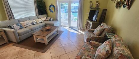 A living room with a grey sofa, a floral sofa, a coffee table, and a TV on a cabinet.