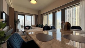A modern hotel room with a large bed, a dining area, and a balcony with a city view. - Luxury Burj Royale 4bed With Balcony Burj Khalifa Fountain View (Dubai)