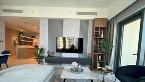 A modern living room with a large flat-screen TV, a sofa, a coffee table, and a dining area in the background. - Luxury Burj Royale 4bed With Balcony Burj Khalifa Fountain View (Dubai)