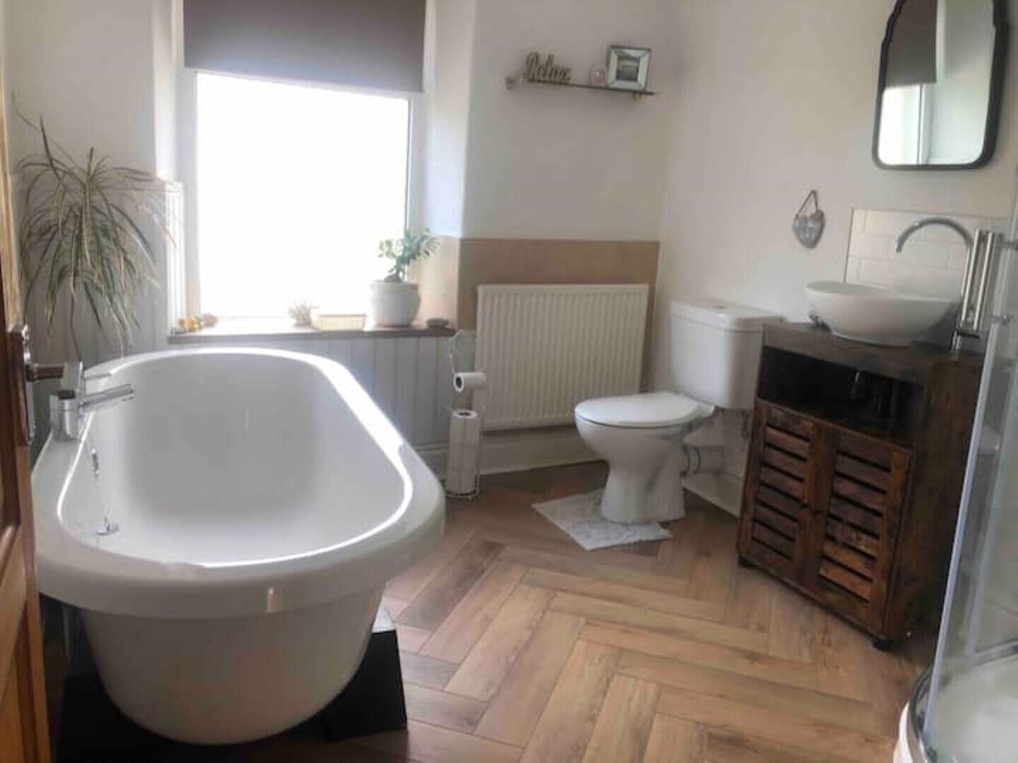 Ein Badezimmer mit freistehender Badewanne, Toilette, Waschbecken und Handtuchwärmer.