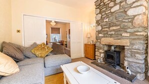 A cozy living room with a stone fireplace, a grey sofa, and a white coffee table.