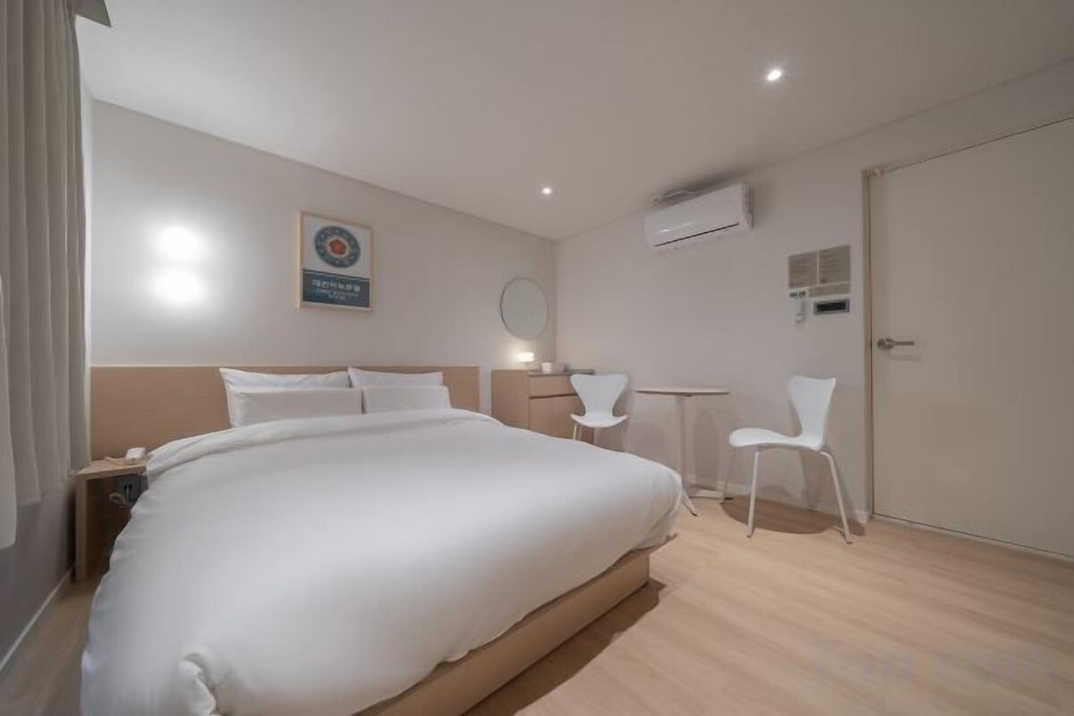 Ein Hotelzimmer mit einem großen Bett, einem Schreibtisch, einem Stuhl und einer Tür.