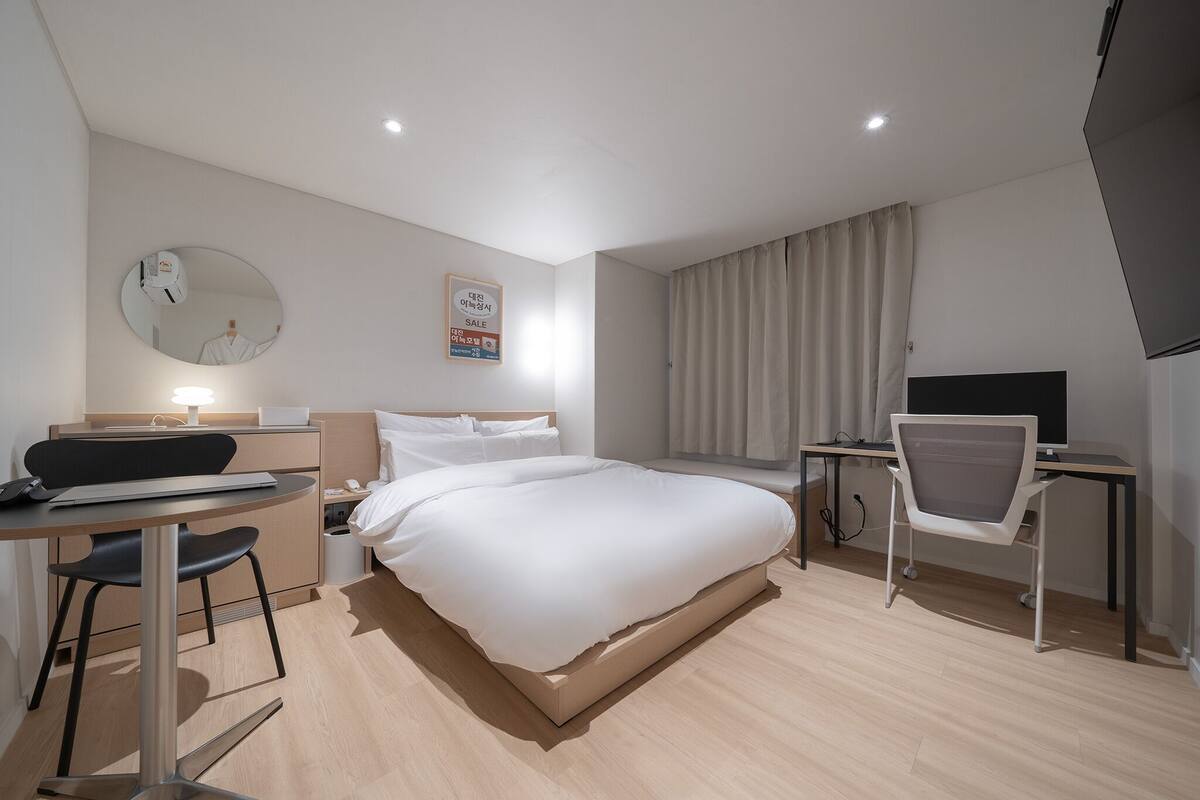 Una habitación de hotel moderna con cama, escritorio, silla y televisión.