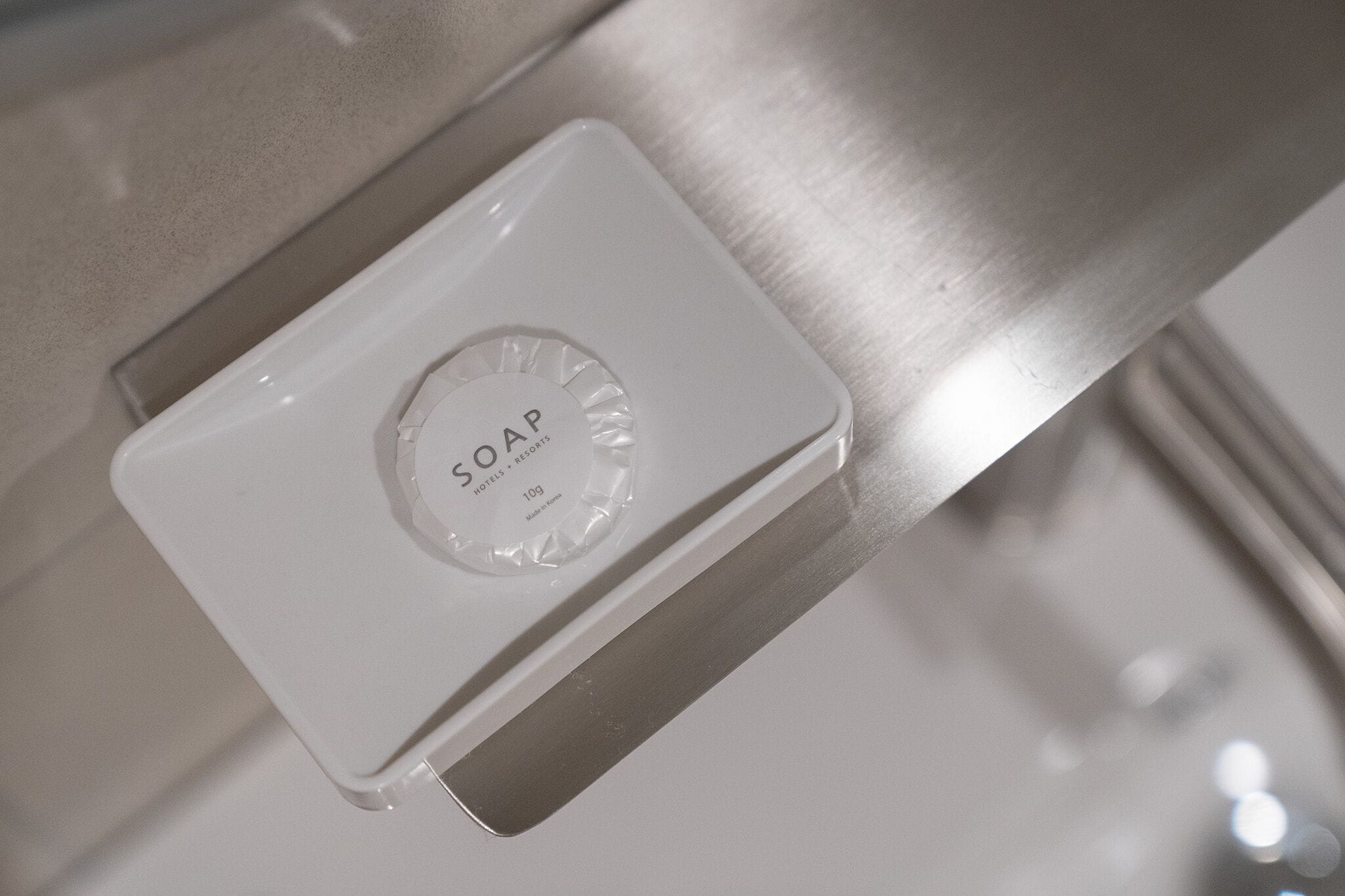 A white soap dispenser on a metallic surface.
