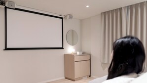 A modern room with a large blank projection screen, a small bedside table with a lamp, and a mirror on the wall. - Anook Hotel Daejeon Daeheung (Daejeon)