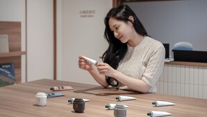 A person sitting at a wooden table with various cosmetic products. - Anook Hotel Daejeon Daeheung (Daejeon)