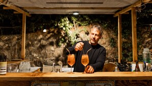 A person at a bar counter with two glasses of a beverage, a bottle, and various bar tools. - Holiday Eolie Village (Lipari)