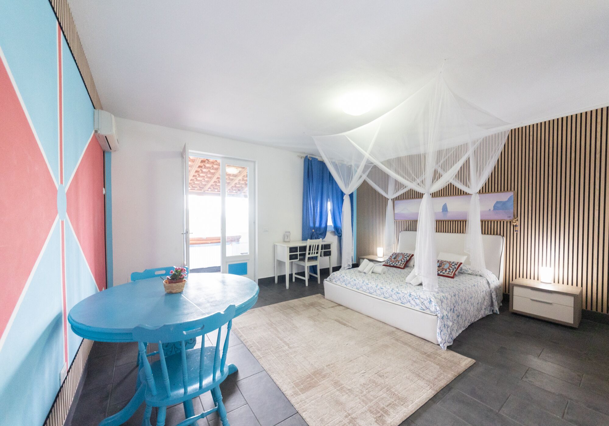 Ein Schlafzimmer mit Bett, Schreibtisch, Stuhl, Tisch und Fenster.