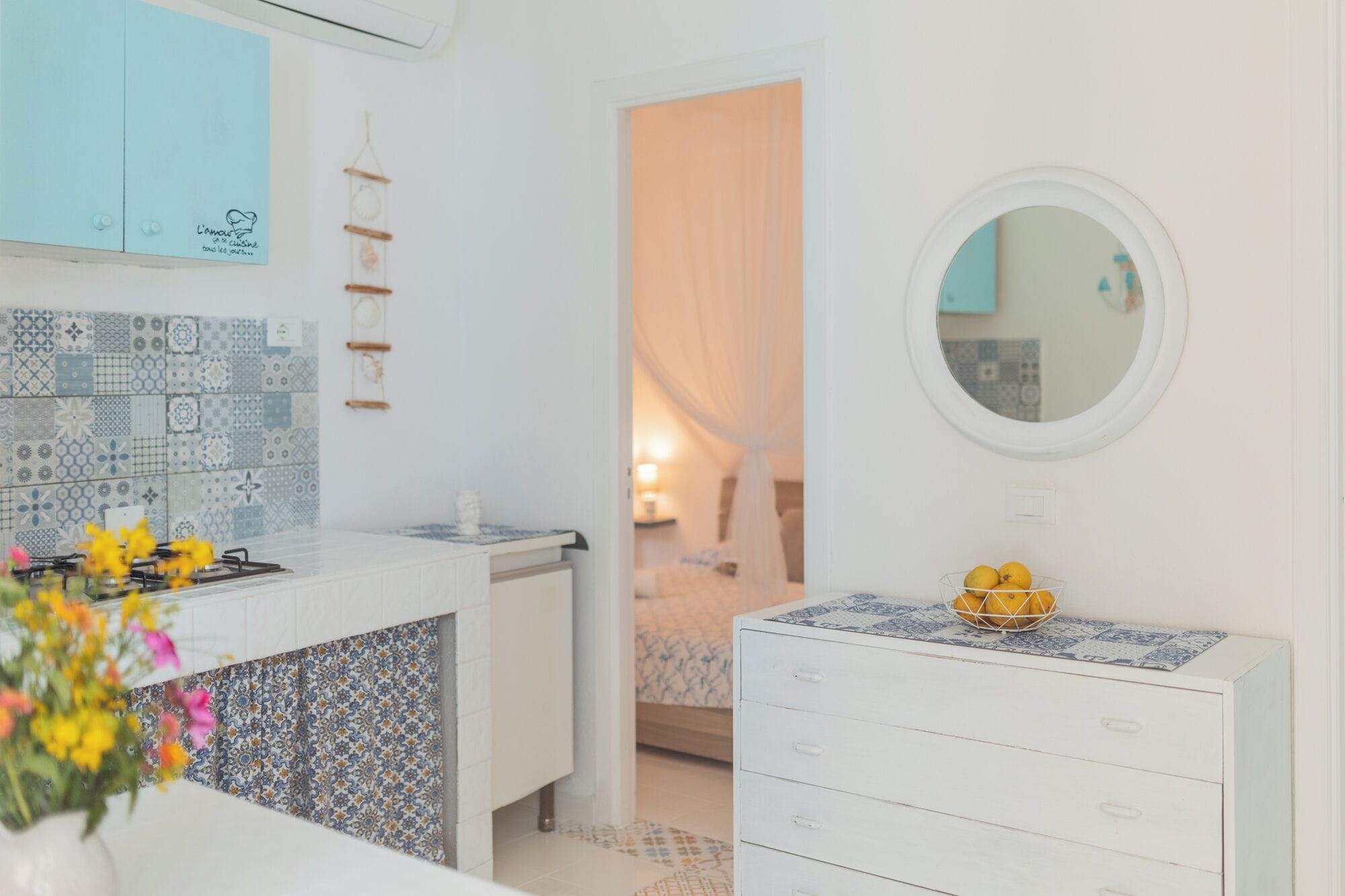 A modern kitchen with patterned tiles, a white stove, and a vase of flowers.