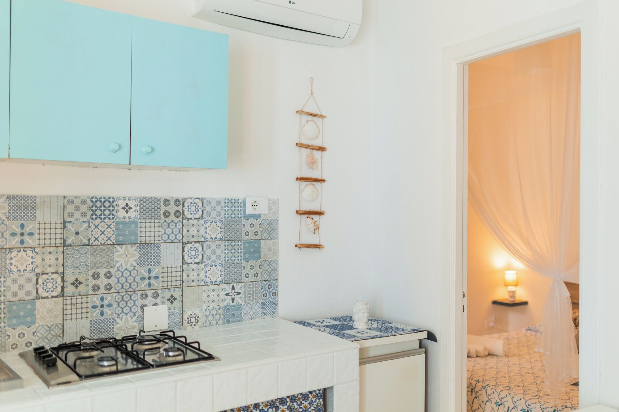 Une cuisine équipée d’une cuisinière à gaz, d’un meuble bleu et d’un pare-feu en carreaux.