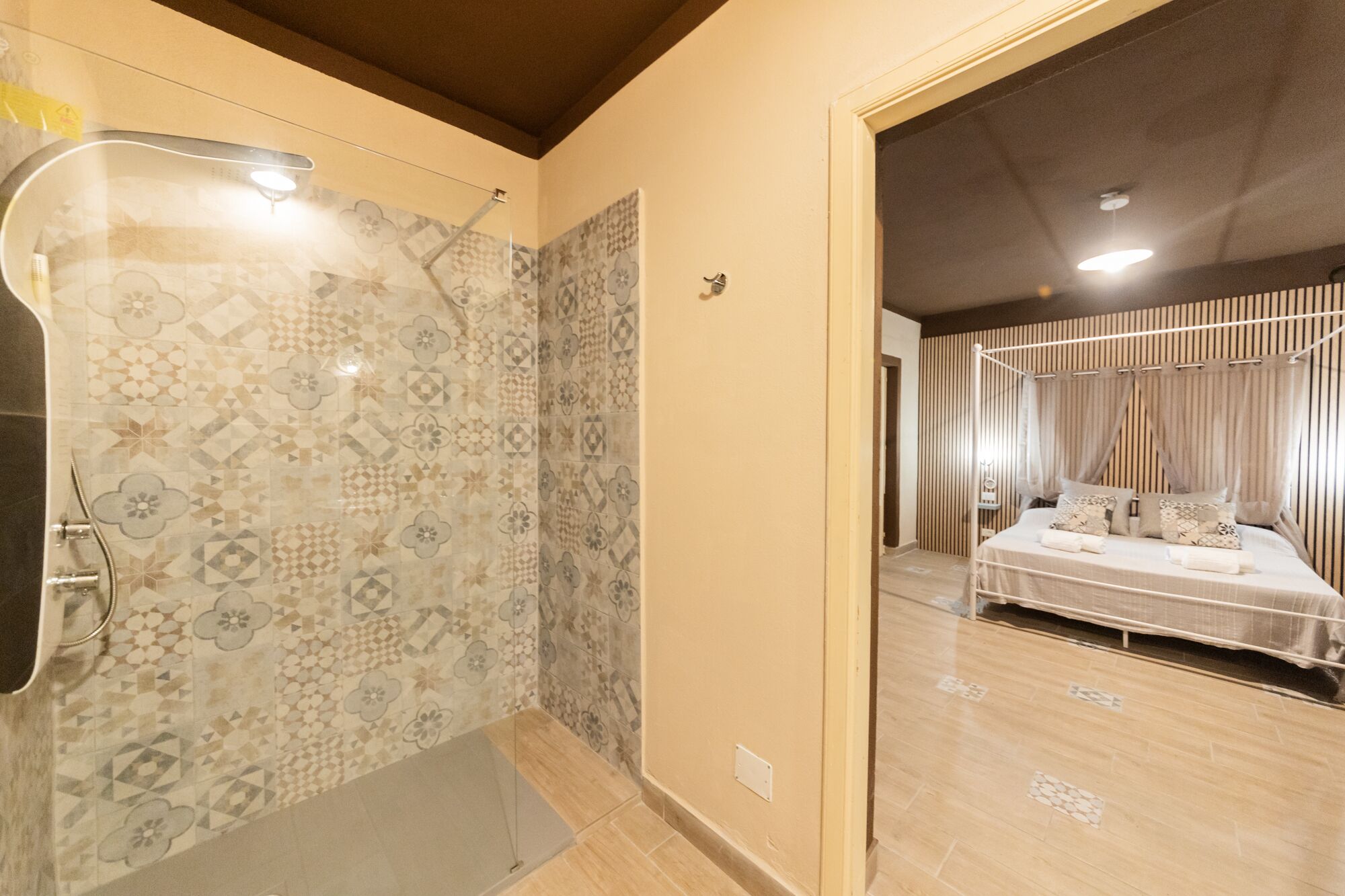Un baño con ducha y un dormitorio con cama y cortinas.
