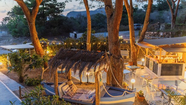 A beachside restaurant with outdoor seating, including a boat-shaped lounge and a bar area. - Holiday Eolie Village (Lipari)