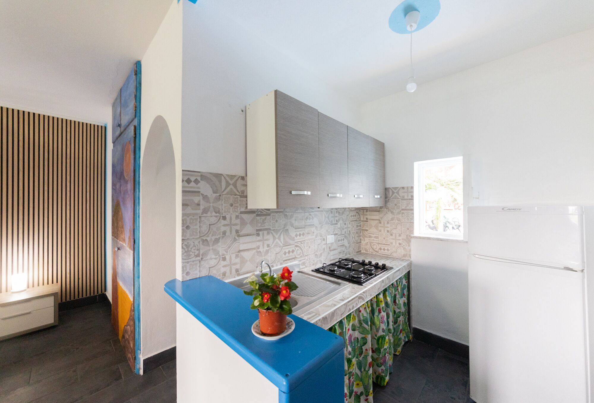A modern kitchen with a blue countertop, a gas stove, and a refrigerator.