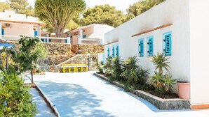 A coastal building with blue shutters, a stone staircase, and a pool area. - Holiday Eolie Village (Lipari)