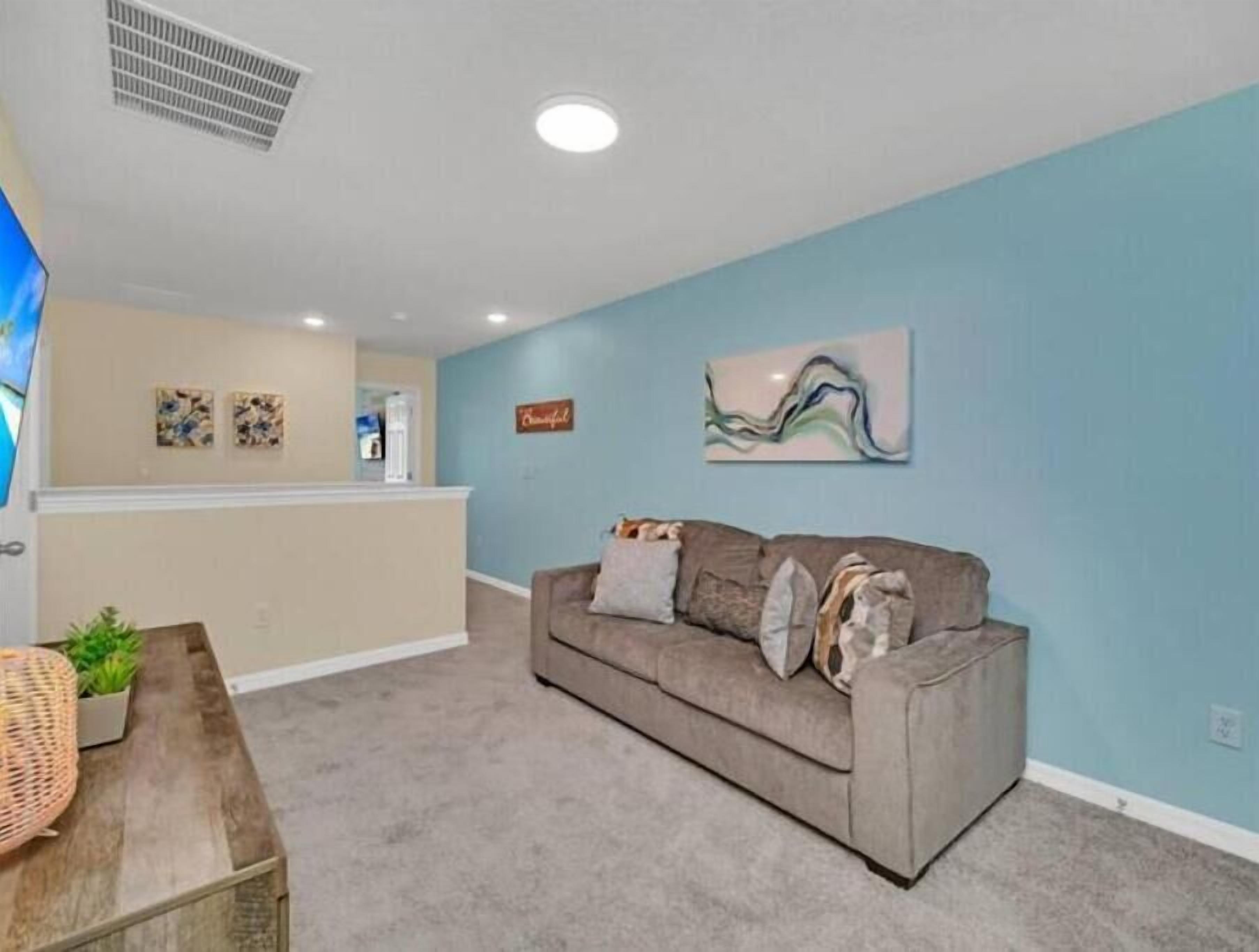 A living room with a grey sofa, a wooden coffee table, and a blue accent wall.