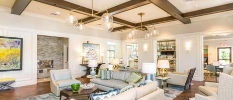 A spacious living room with a high ceiling, exposed beams, and a large window.
