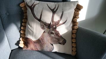 A pillow with a deer illustration on a grey upholstered chair.