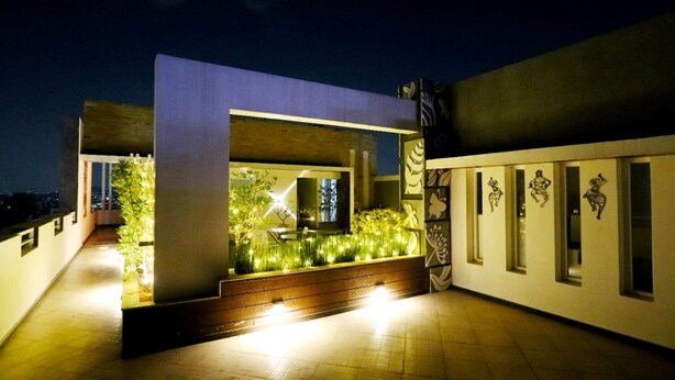 Un bâtiment moderne doté d’une grande baie vitrée, d’un balcon agrémenté de plantes et d’un chemin menant à l’entrée.