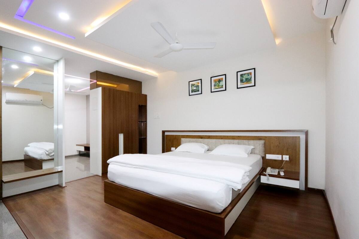 Habitació d'hotel moderna amb un llit de fusta, un ventilador de sostre i un mirall.