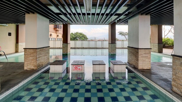 An indoor swimming pool with a checkered floor, pillars, and a view of buildings in the background. - OYO Life 92910 Apartemen Tamansari Panoramic By Tira (Bandung)
