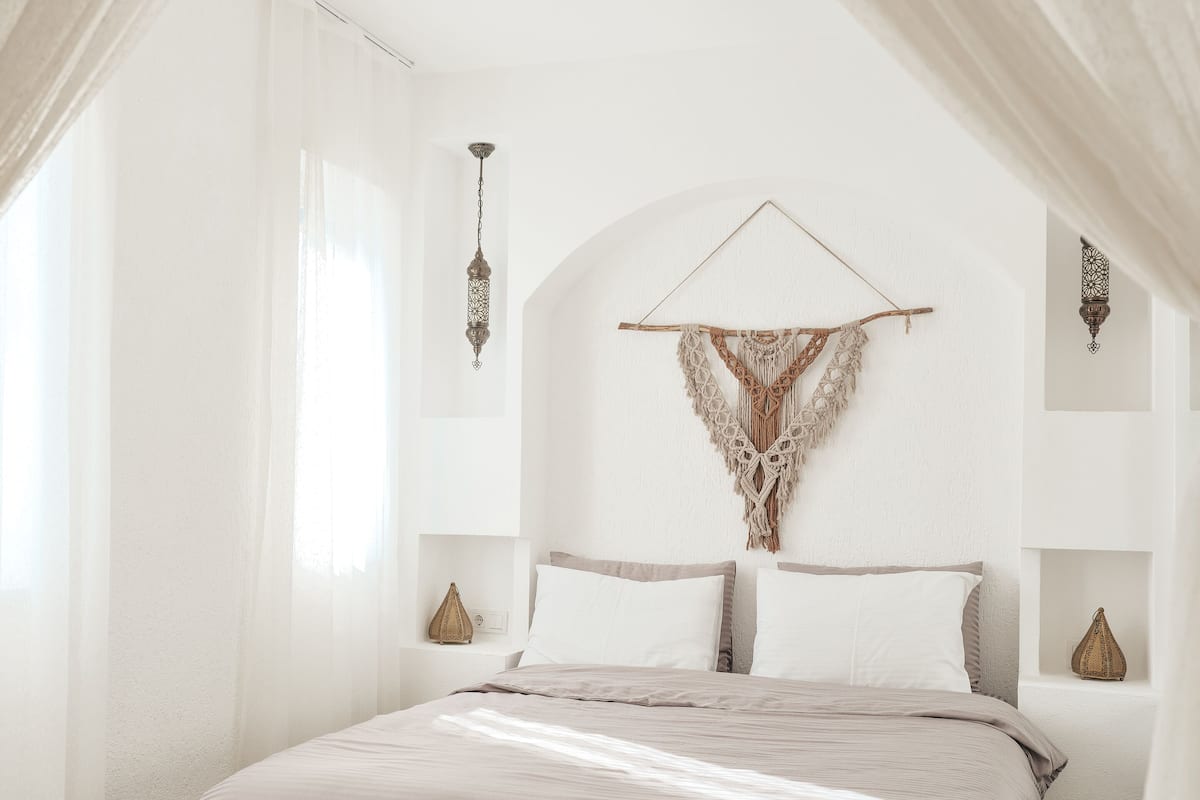 A bedroom with a bed, white walls, and a ceiling light.