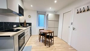 Une cuisine compacte avec un coin repas, un plancher en bois et une fenêtre qui laisse entrer la lumière naturelle.