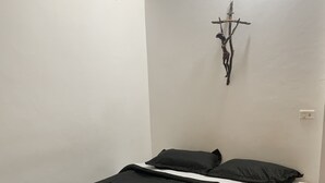 Et værelse med en seng, en lampe på væggen og en hvid væg.