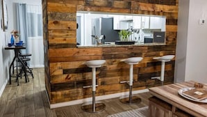 Une cuisine moderne avec un mur d’accent en bois, un îlot central doté de tabourets de bar et un comptoir de cuisine bien visible.