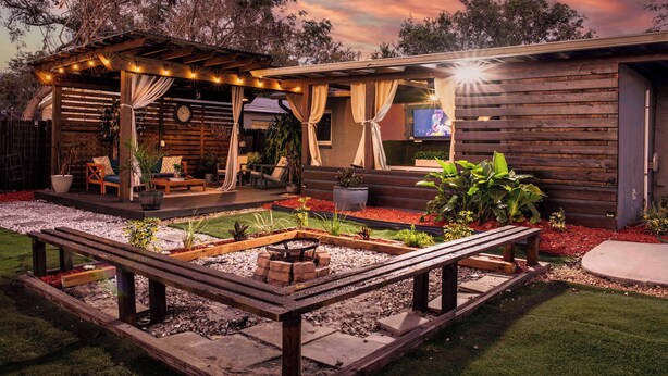 Un espace extérieur aménagé avec une pergola en bois, des sièges et un foyer.