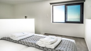 Habitación de hotel con una cama grande, dos almohadas y un ventanal con vistas.