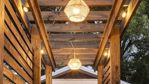 Una pérgola de madera con un sendero de ladrillo que lleva a una puerta.