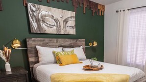 A bedroom with a wooden bed frame, a green accent wall, and a ceiling fan.