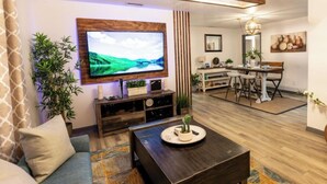A living room with a TV, sofa, coffee table, and a dining area with a table and chairs.
