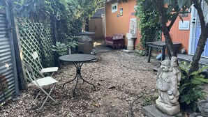 A patio area with a table and chairs, a trash bin, and a statue. - LA CASITA ON EAST 7TH STREET (Austin)