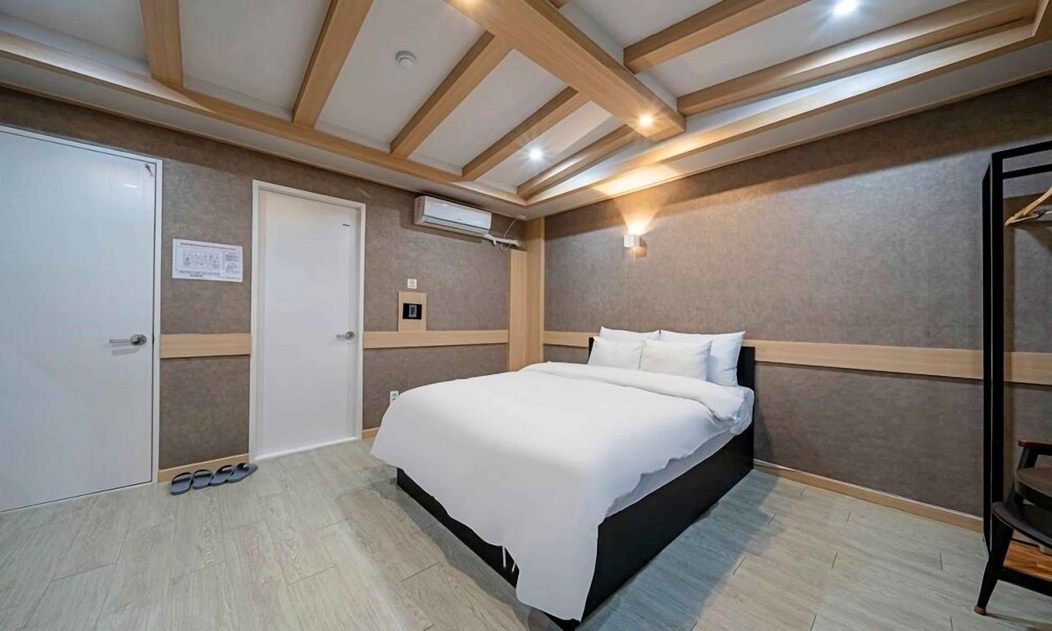 A bedroom with a bed, a wardrobe, a door, and a shoe rack.