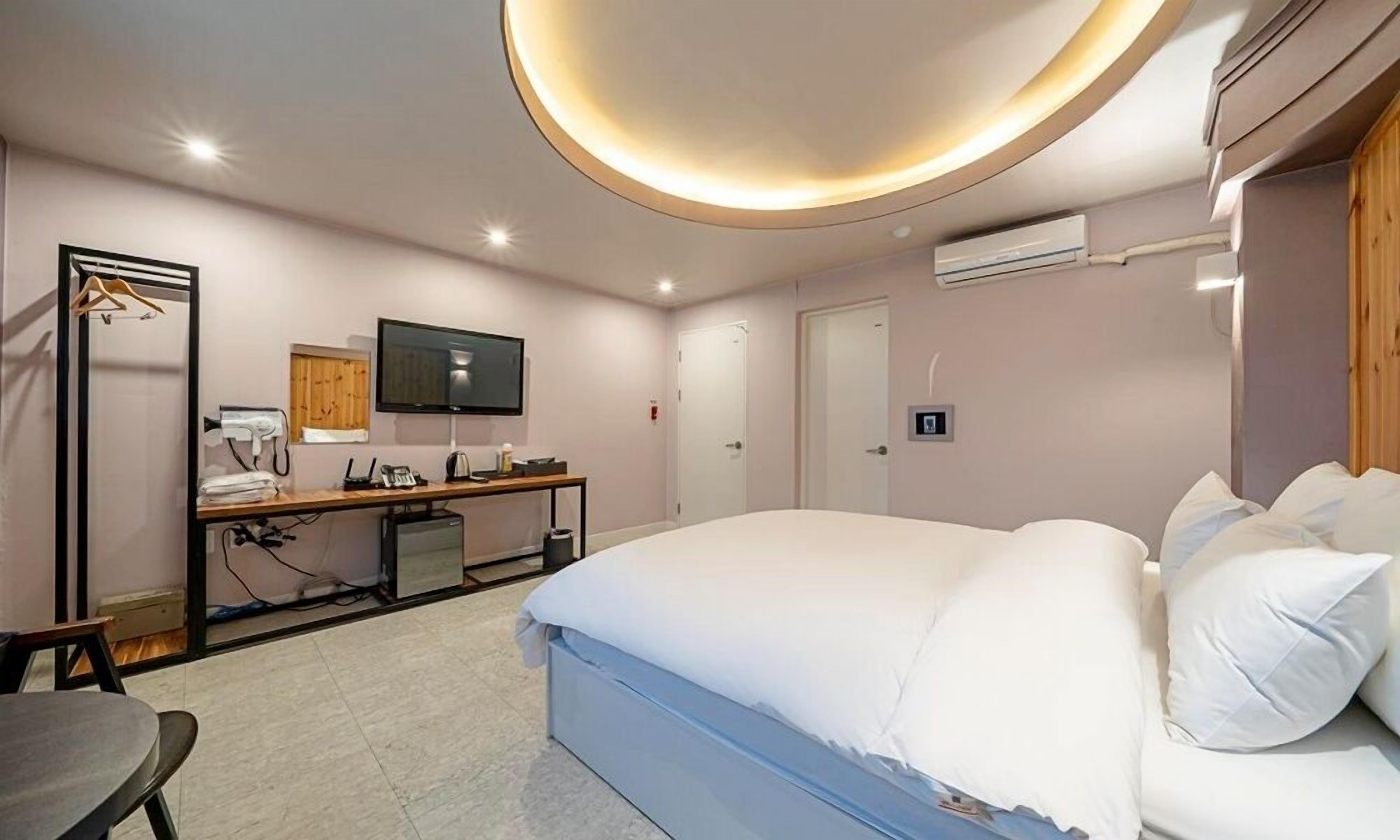 Een hotelkamer met een bed, een bureau met een flatscreen televisie, een kledingkast en een airconditioner.