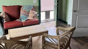 A room with a red sofa, a wooden table, and wicker chairs. - The Aspen at Hamilton Cove ~ Cabin Eleven ~ Pet Friendly (Royal)