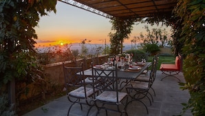An outdoor dining area with a table set for four, surrounded by chairs, overlooking a scenic sunset view. - Casa Lionardo, Vinci, Florence and Chianti (Vinci)