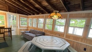 L’intérieur d’un chalet rustique, avec une table hexagonale, des murs en bois et de grandes fenêtres.