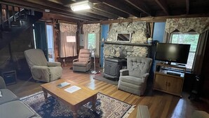 Un salon chaleureux avec une cheminée en pierre, des fauteuils confortables et un téléviseur.