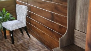 Een kamer met een houten vloer met een mozaïekpatroon, een witte gestoffeerde stoel en een houten bank met een gebogen rugleuning.
