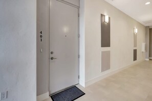 Un pasillo con una puerta marcada '401', iluminación empotrada en la pared y un felpudo.