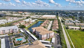 Un quartier résidentiel comprenant un grand immeuble à plusieurs étages, un parking et un petit lac.