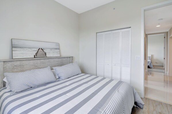 Une chambre à coucher avec un lit, une tête de lit, une armoire et un tableau accroché au mur.
