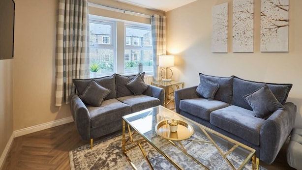 A modern living room with two grey sofas, a glass coffee table, and a patterned rug. - Host & Stay | Studio No.8 (Alnwick)