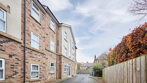 A narrow street flanked by two-story brick buildings with visible windows and a wooden fence on one side. - Host & Stay | Studio No.8 (Alnwick)