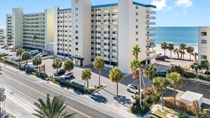 Un hotel de varios pisos con una torre central, estacionamiento y vista a la playa.